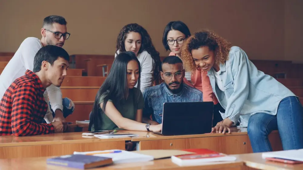 Diverse group of students gathered around laptop, illustrating community-led storytelling